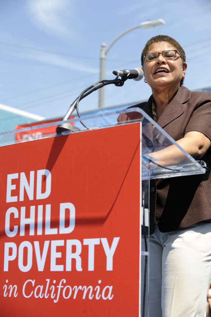 Congressmember Karen Bass speaks in front of a podium that says "End Child Poverty in California" at an End Child Poverty rally, April 2017. Photo credit: Valerie Goodloe