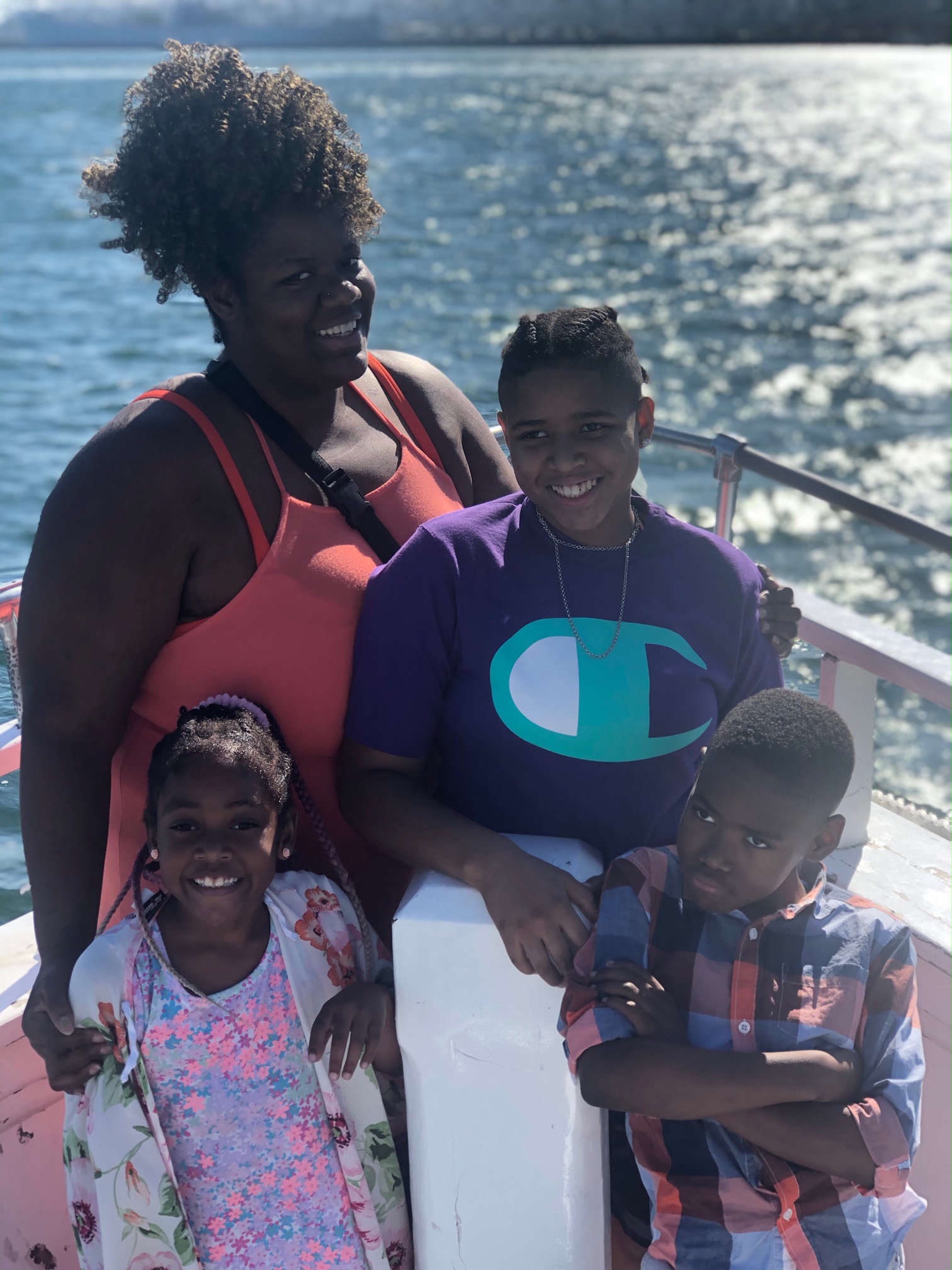 Mom-of-three and law student Sabrina poses with her children and a beautiful lake with sun streaks in the background