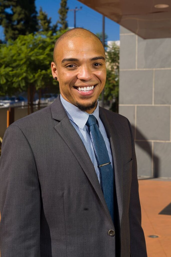 A picture of Kenneth Chancey from National Foster Youth Institute standing outside a building smiling in a suit