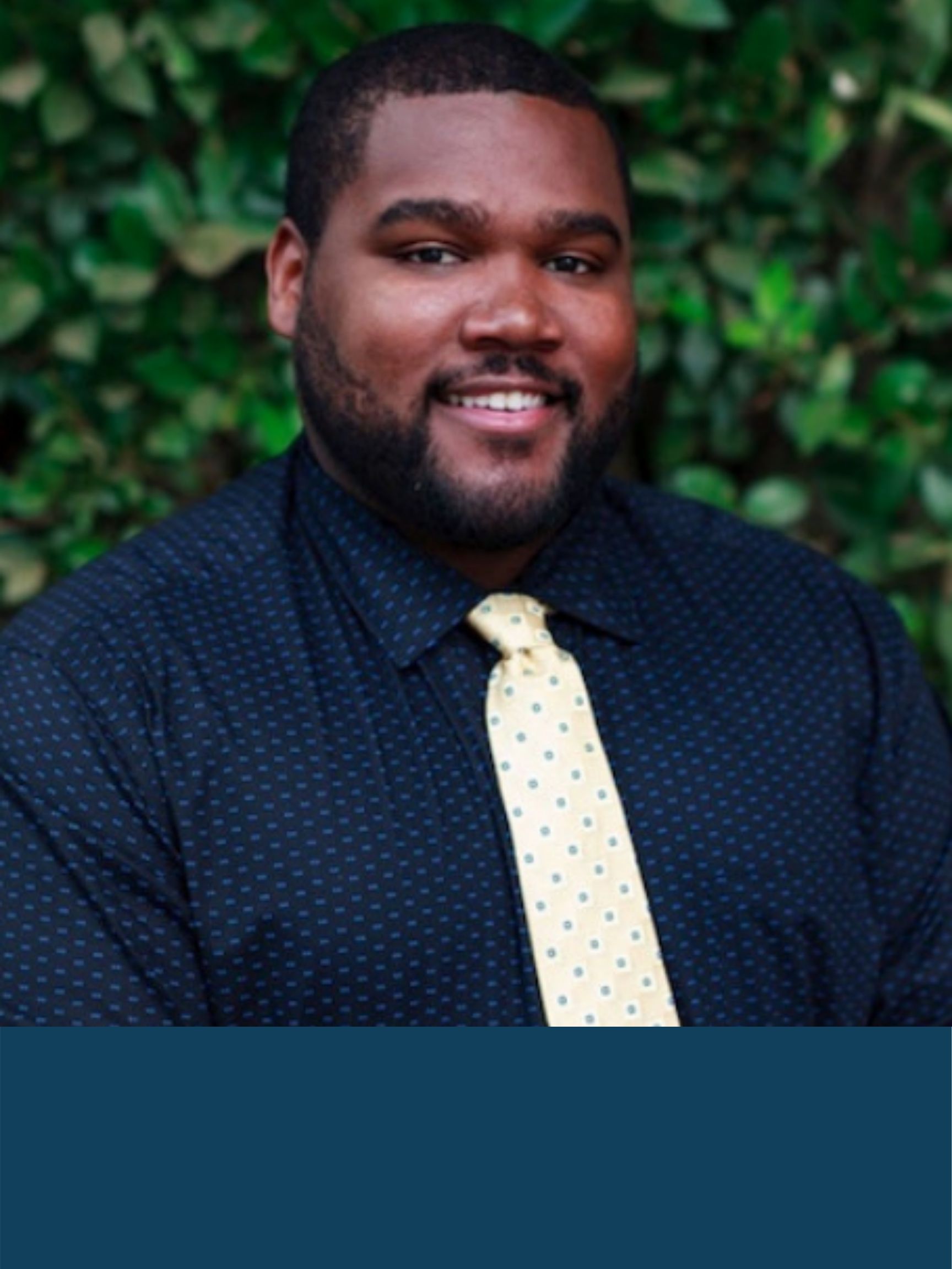 A formal portrait of Jevon Wilkes, Executive Director of California Coalition for Youth, wearing a button down shirt and yellow tie